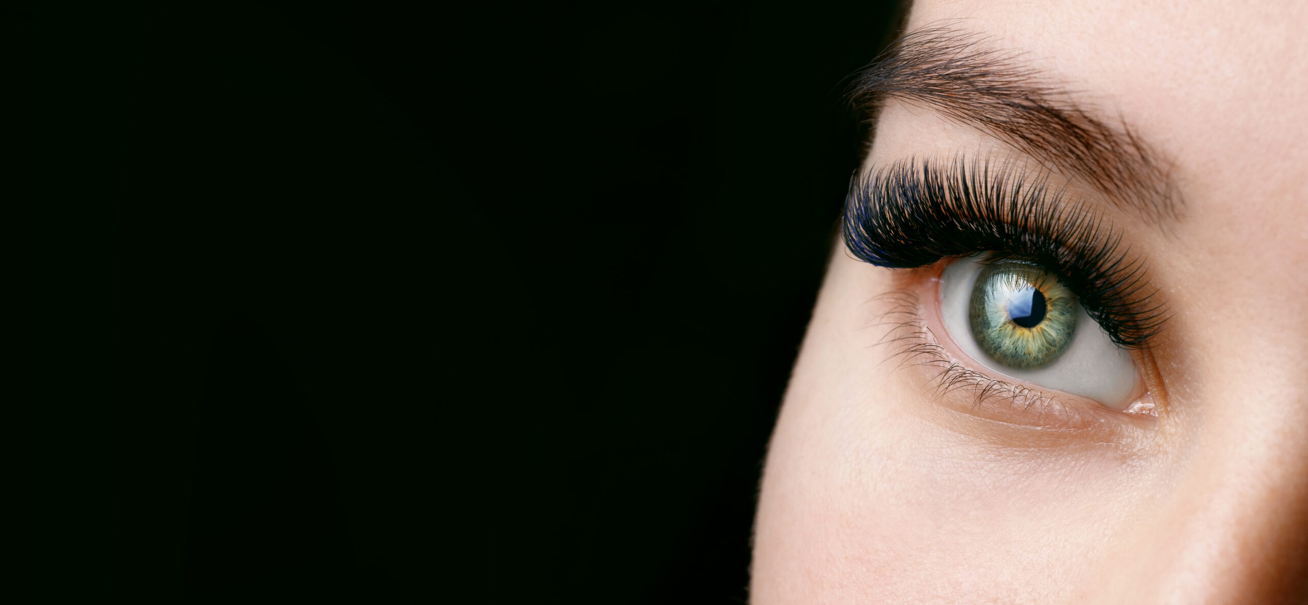 Close-up of a green eye framed by full, hand-applied lash extensions